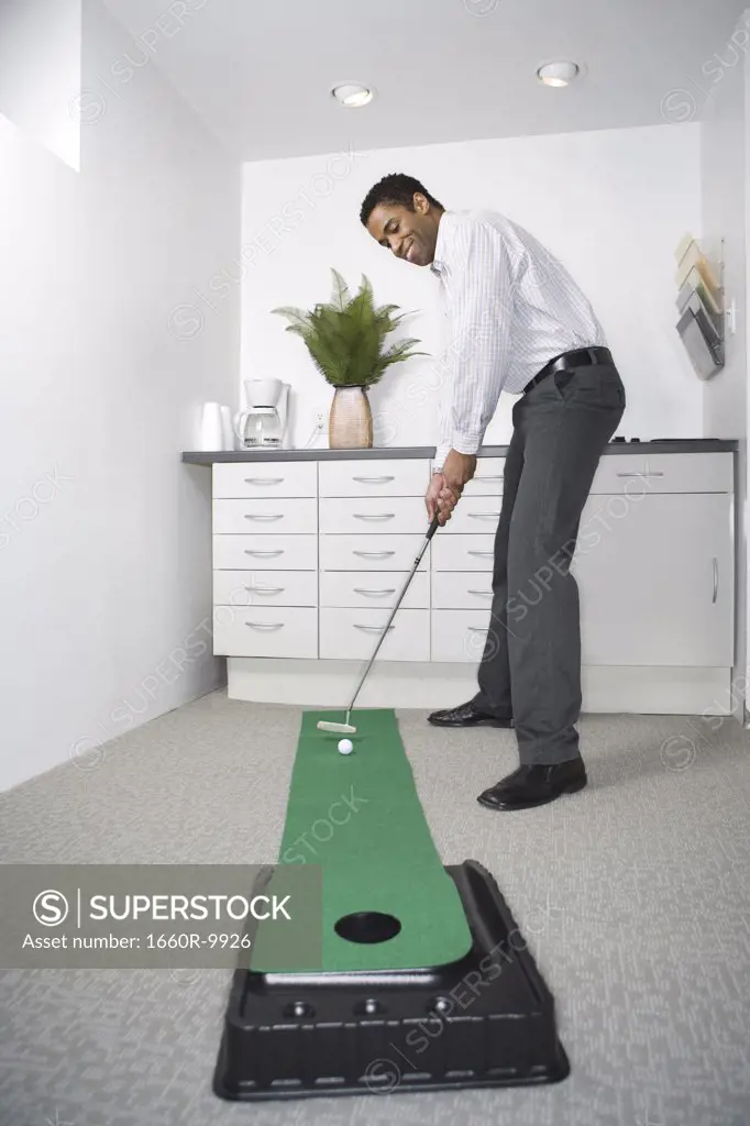 Mid adult man practicing golf in the office