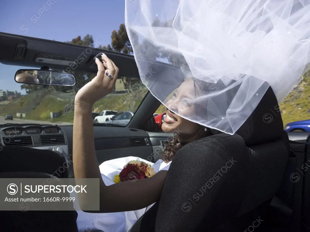 Rear view of a bride sitting with her groom in a convertible car