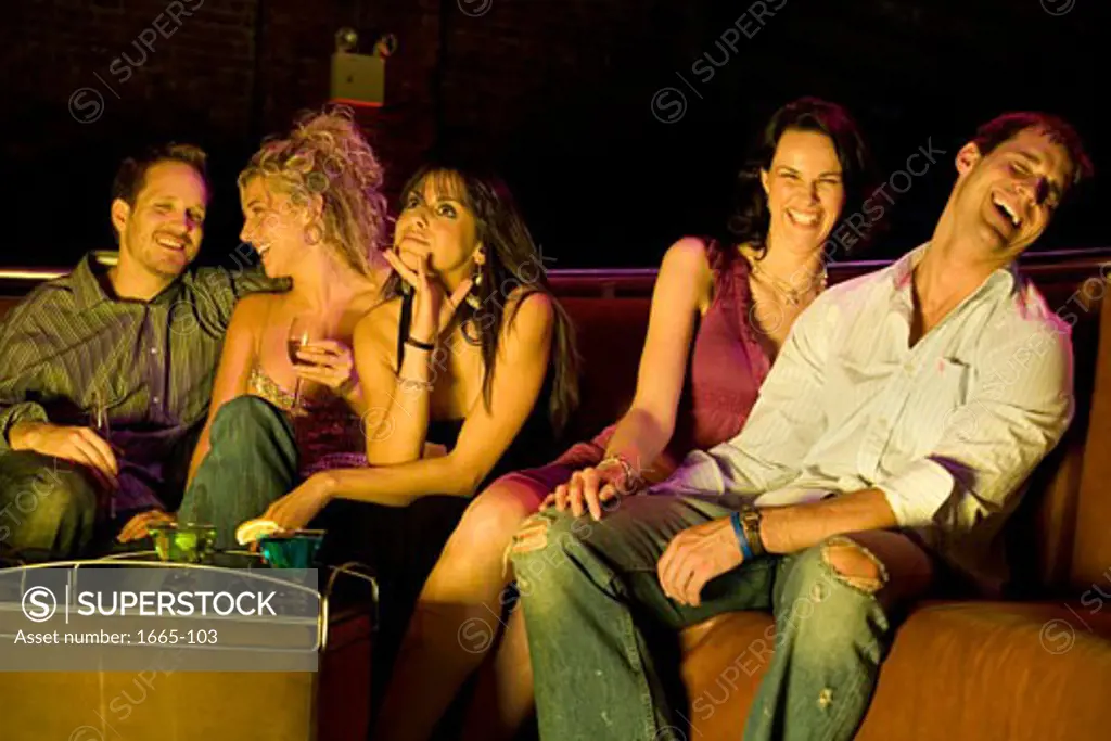 Two young men and three young women sitting in a nightclub