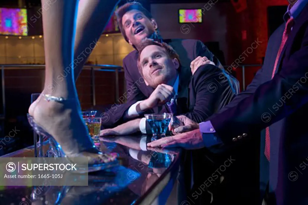 Three young men flirting with a dancer in a nightclub
