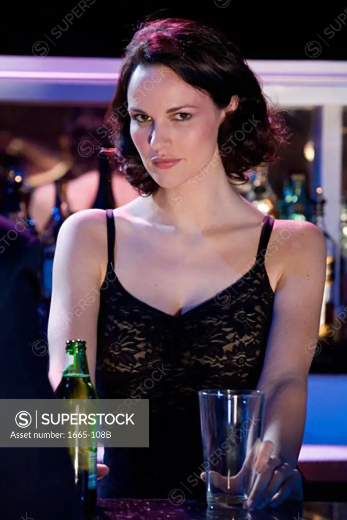 Portrait of a female bartender holding a glass and a beer bottle