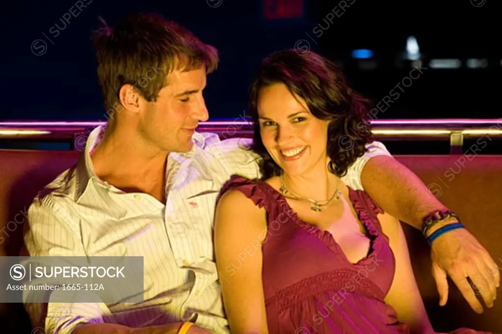 Portrait of a young woman sitting with a young man in a nightclub and smiling