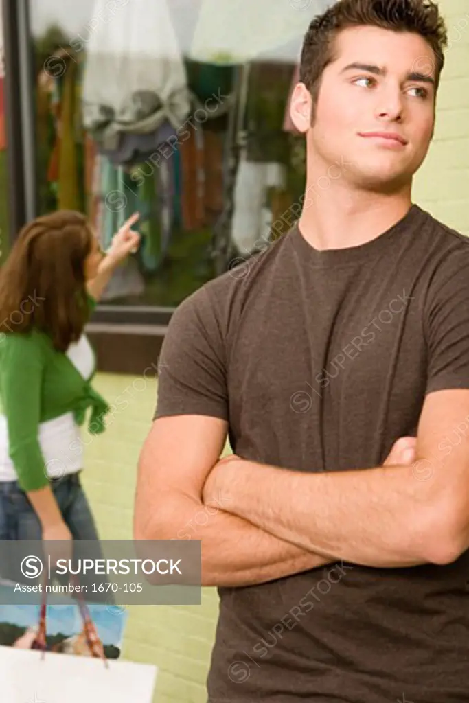 Close-up of a teenage boy looking sideways with a young woman shopping behind him
