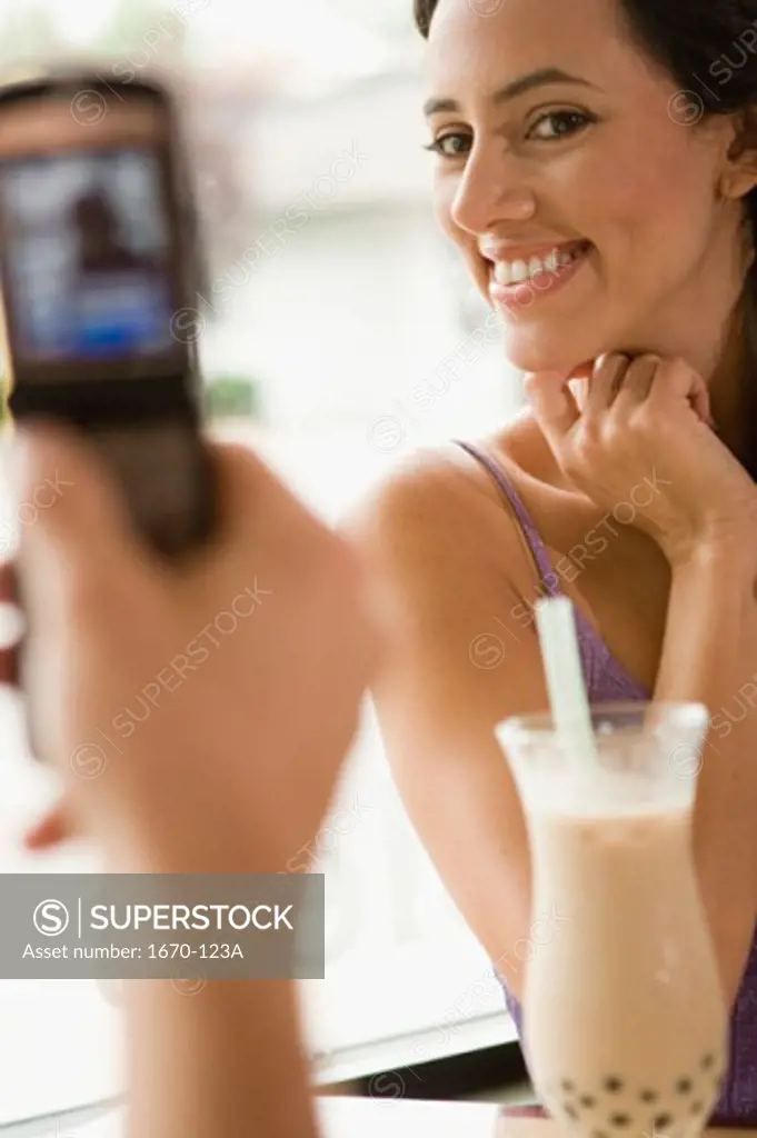 Close-up of a person's hand taking a photograph of a young woman with a mobile phone