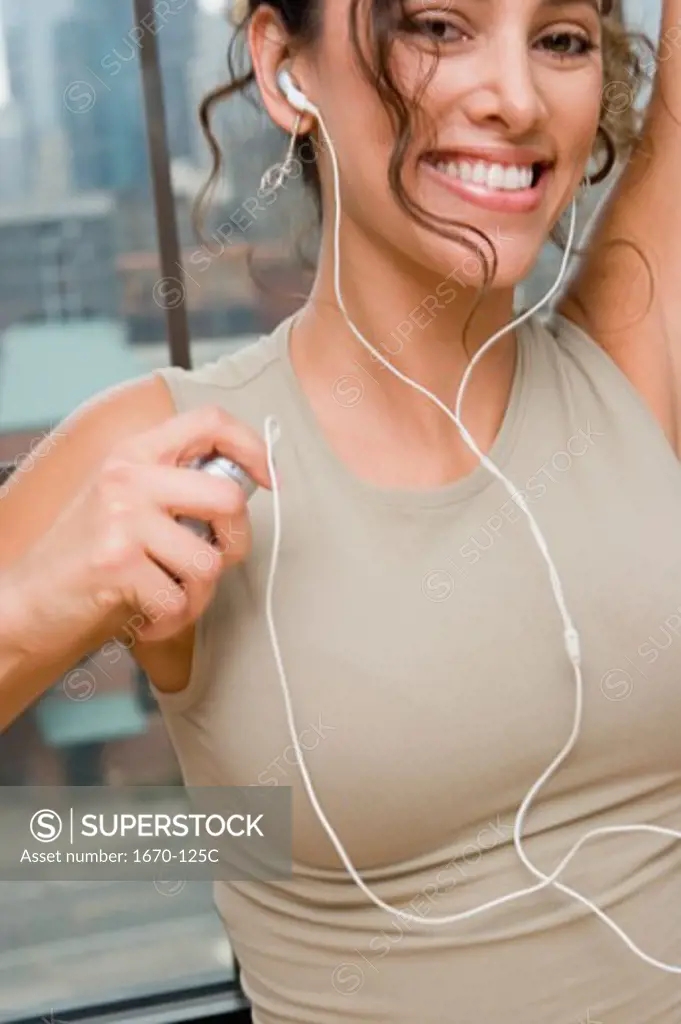 Portrait of a young woman listening to an MP3 Player and smiling