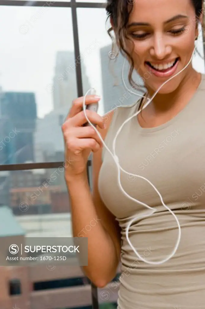 Close-up of a young woman listening to an MP3 Player and smiling