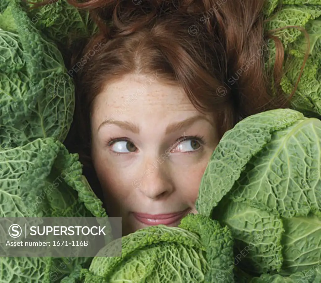 Young woman surrounded by savoy cabbage