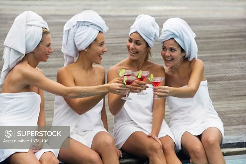 Four young women toasting at poolside