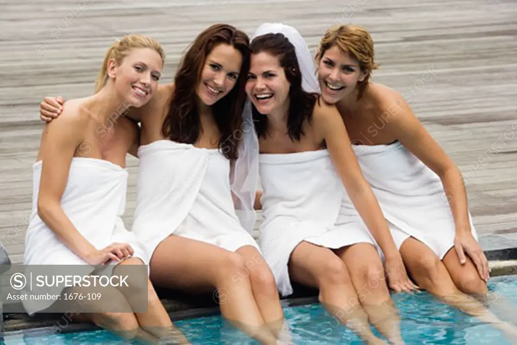Four young women smiling at poolside