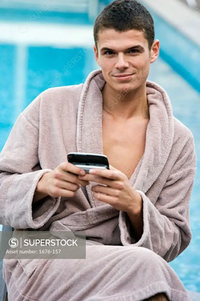 Young man holding a PDA while wearing a bathrobe