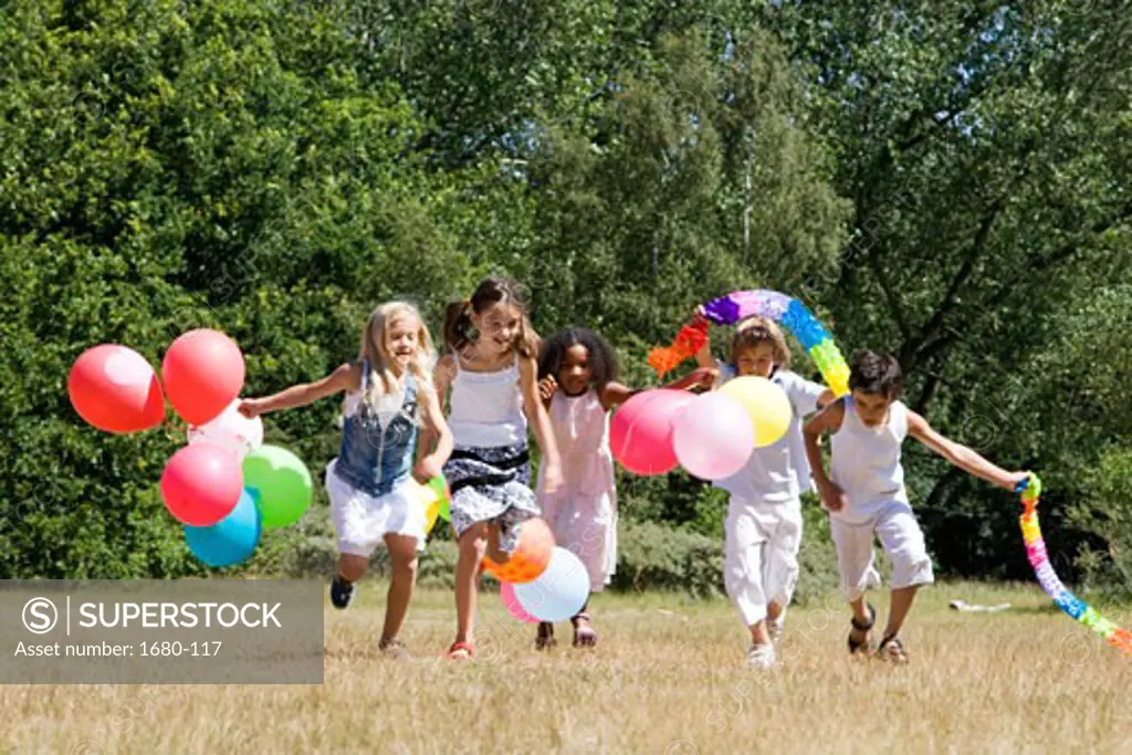 Five children playing with balloons in a park