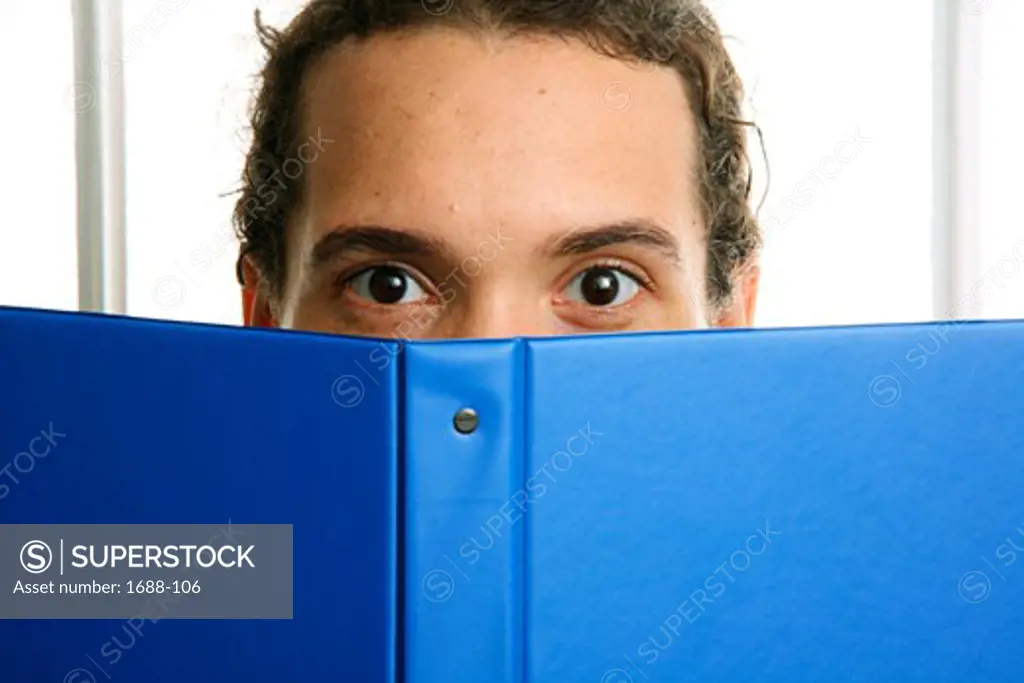 Young man holding a notebook in front of his face