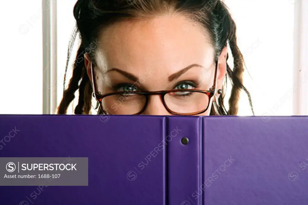 Young woman holding a notebook in front of her face