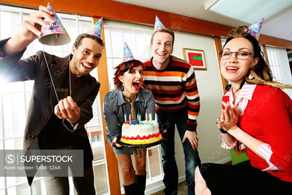 Two businessmen and two businesswomen celebrating a birthday
