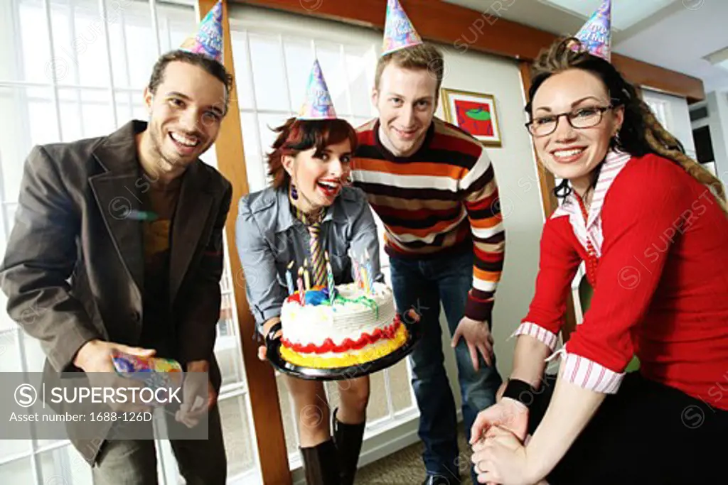Two businessmen and two businesswomen celebrating a birthday