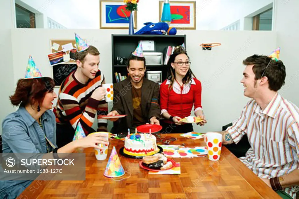 Three businessmen and two businesswomen celebrating a birthday
