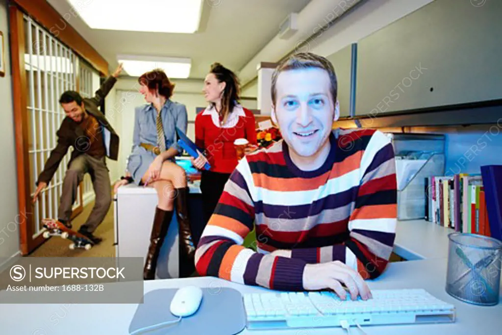 Businessman using a computer with two businesswomen and a businessman behind him