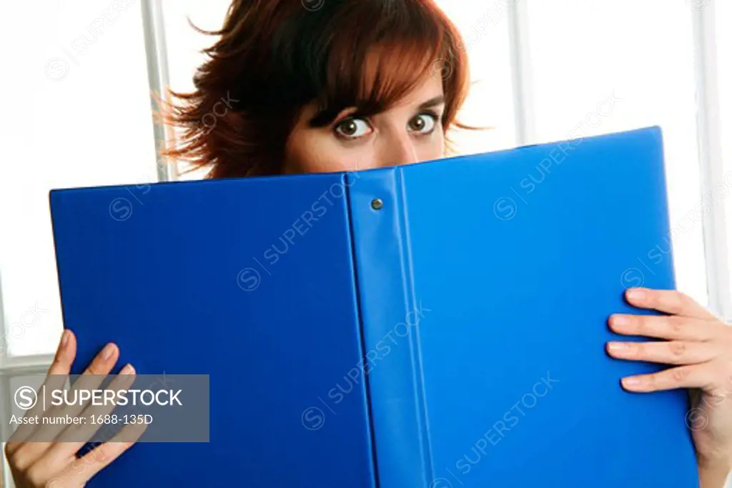 Businesswoman holding a notebook in front of her face