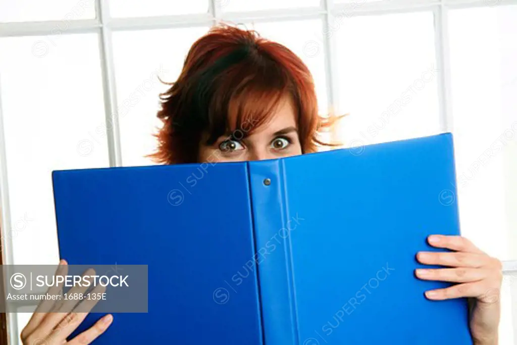 Businesswoman holding a notebook in front of her face