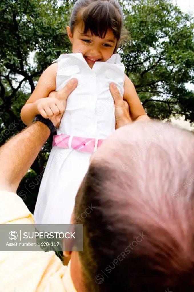 Low angle view of a girl being lifted up by her father