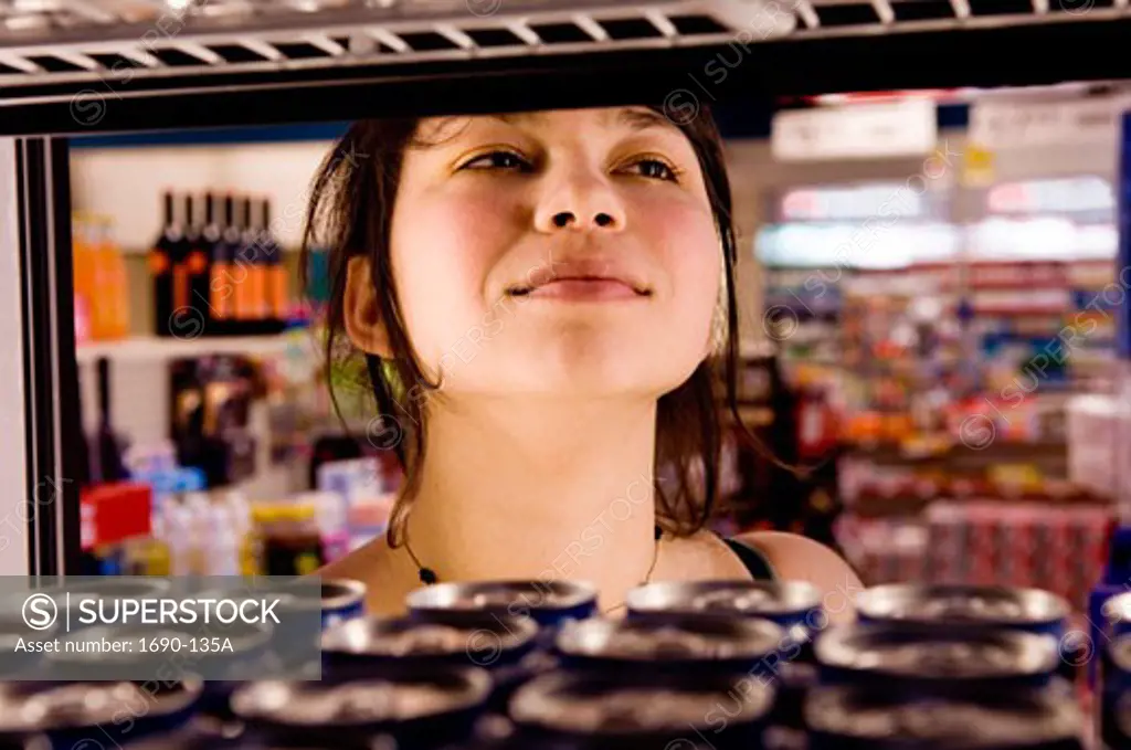 Young woman standing in front of a drink cooler