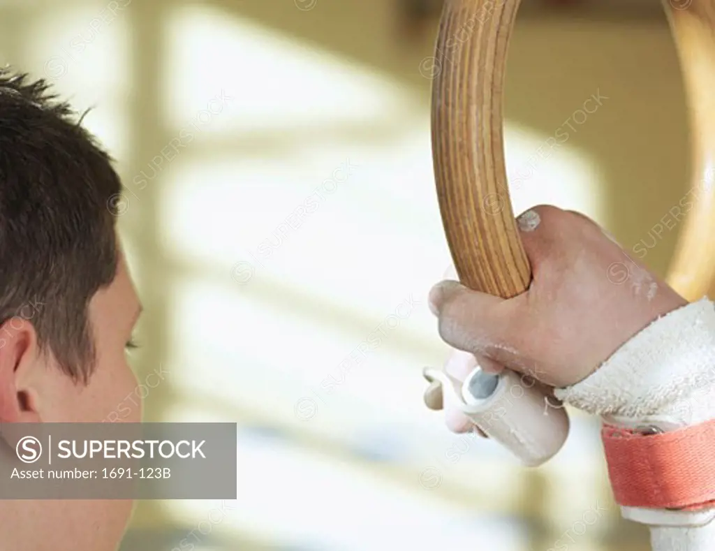 Close-up of a male gymnast holding a gymnastic ring
