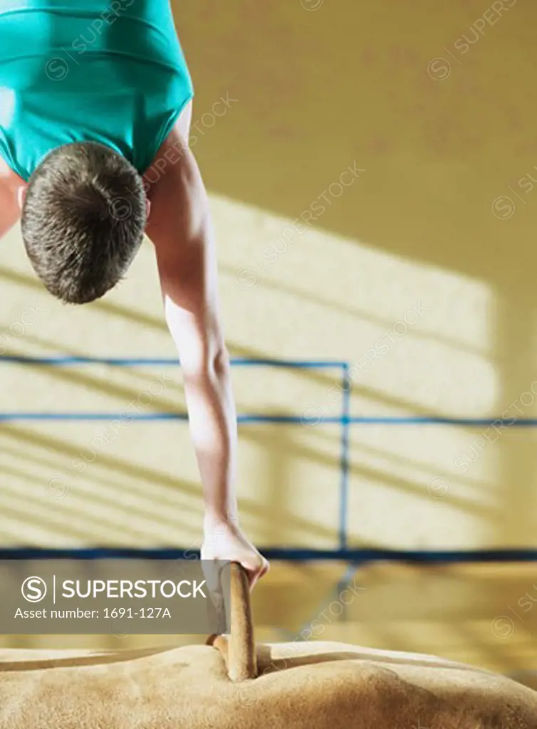 Rear view of a male gymnast performing on a pommel horse