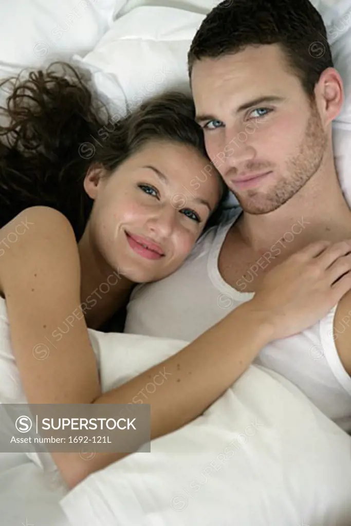 Portrait of a young couple lying in bed