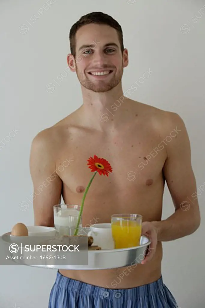 Young man holding a tray of breakfast food and smiling
