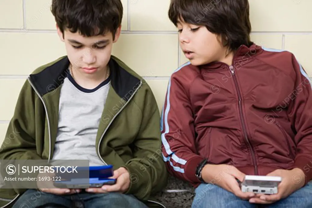 Two boys playing with handheld video games