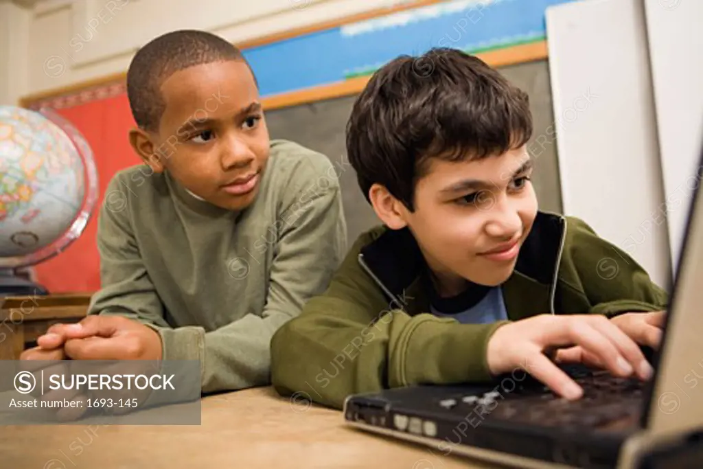 Two boys using a laptop in a classroom
