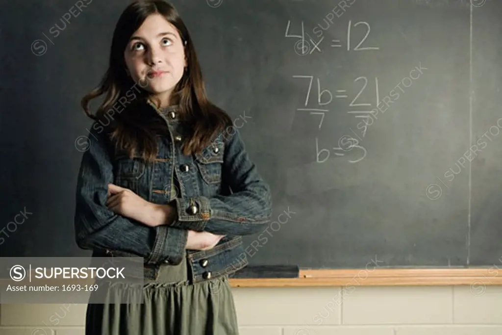 Girl standing in front of a chalkboard looking up