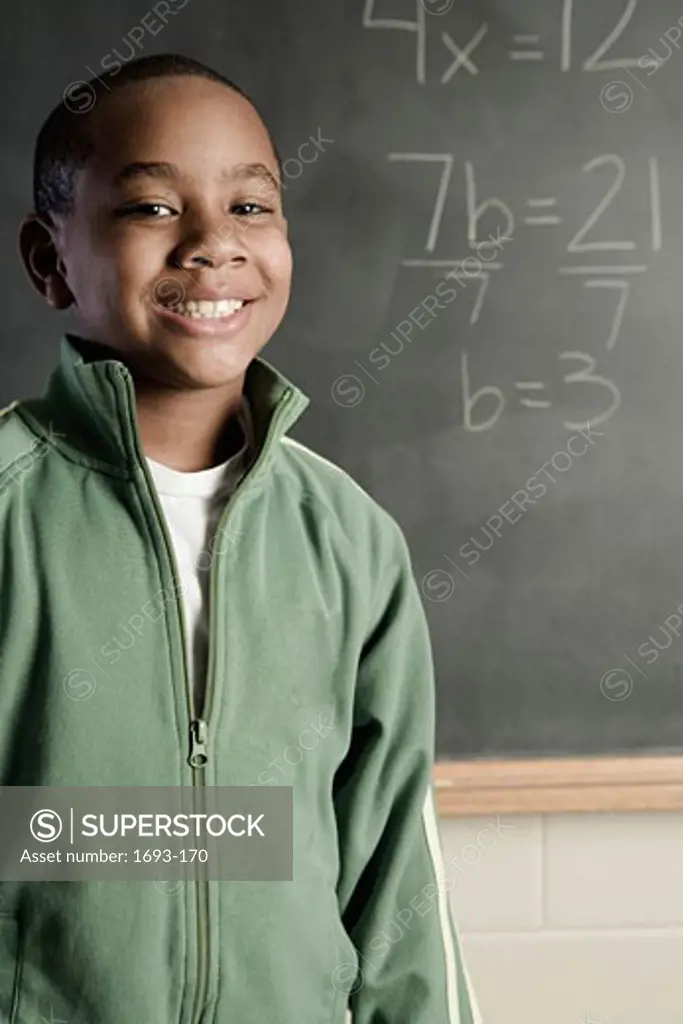 Portrait of a boy standing in front of a chalkboard