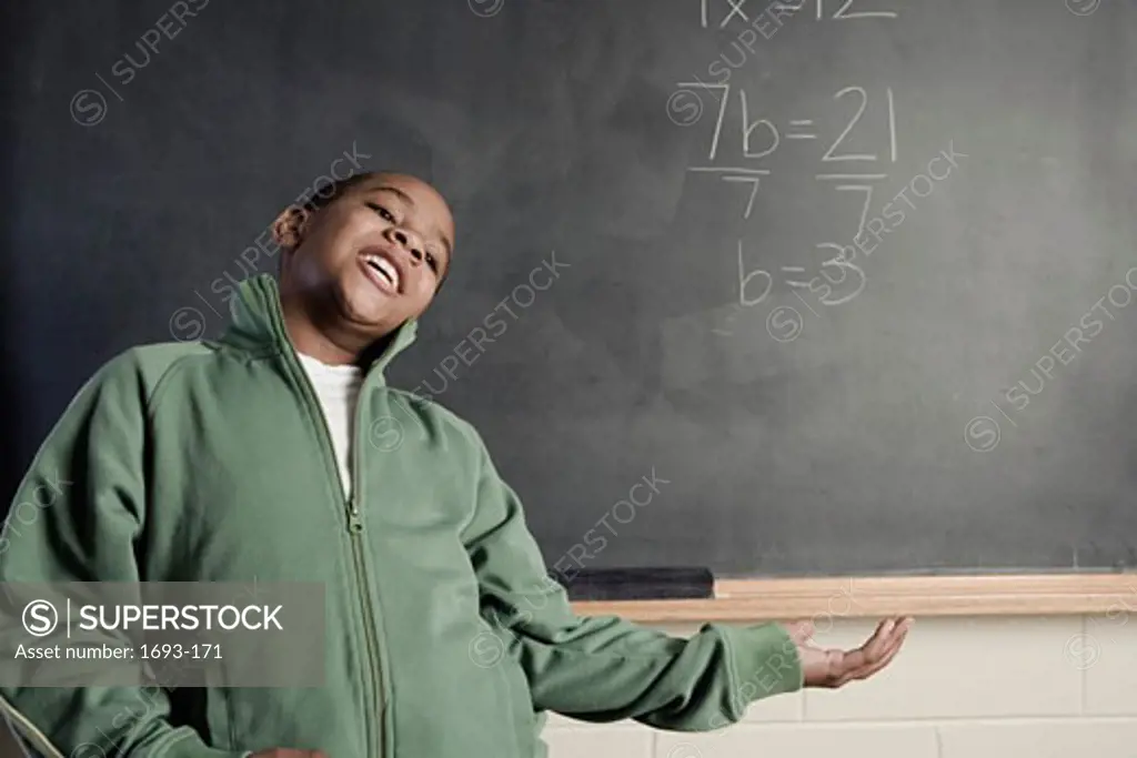 Boy in front of a chalkboard near a math problem