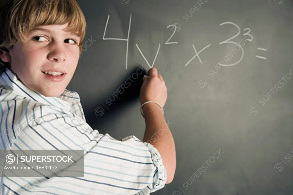 Boy working a math problem on a chalkboard