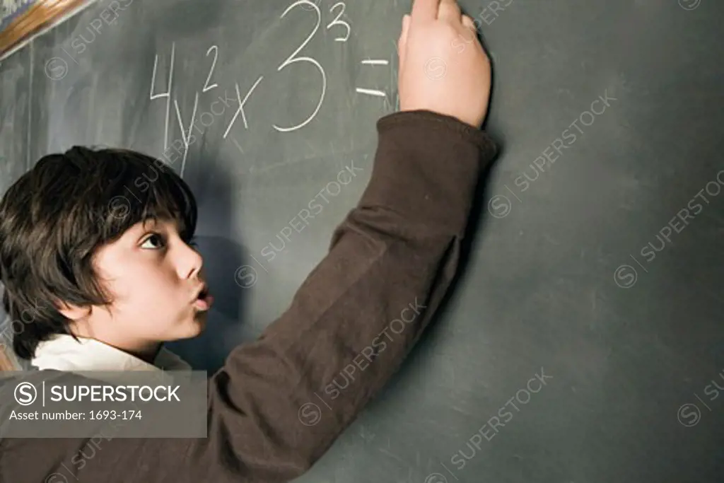 Boy working a math problem on a chalkboard