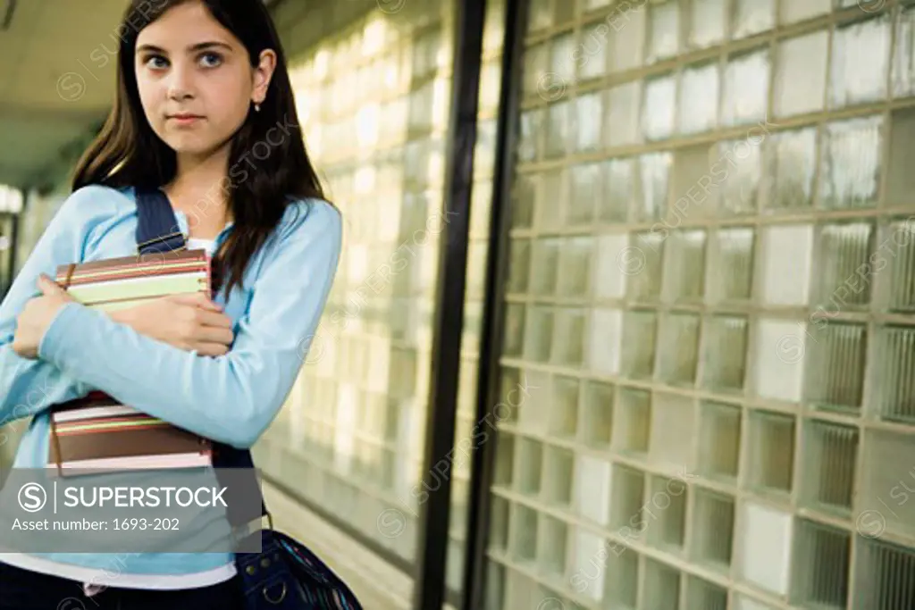 Girl standing in a corridor and holding a notebook