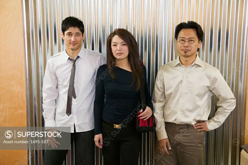 Businesswoman with two businessmen standing in front of a wall