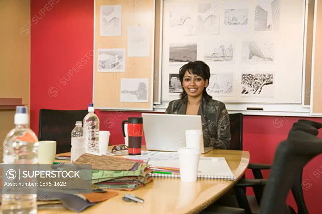 Businesswoman sitting in a conference room in front of a laptop