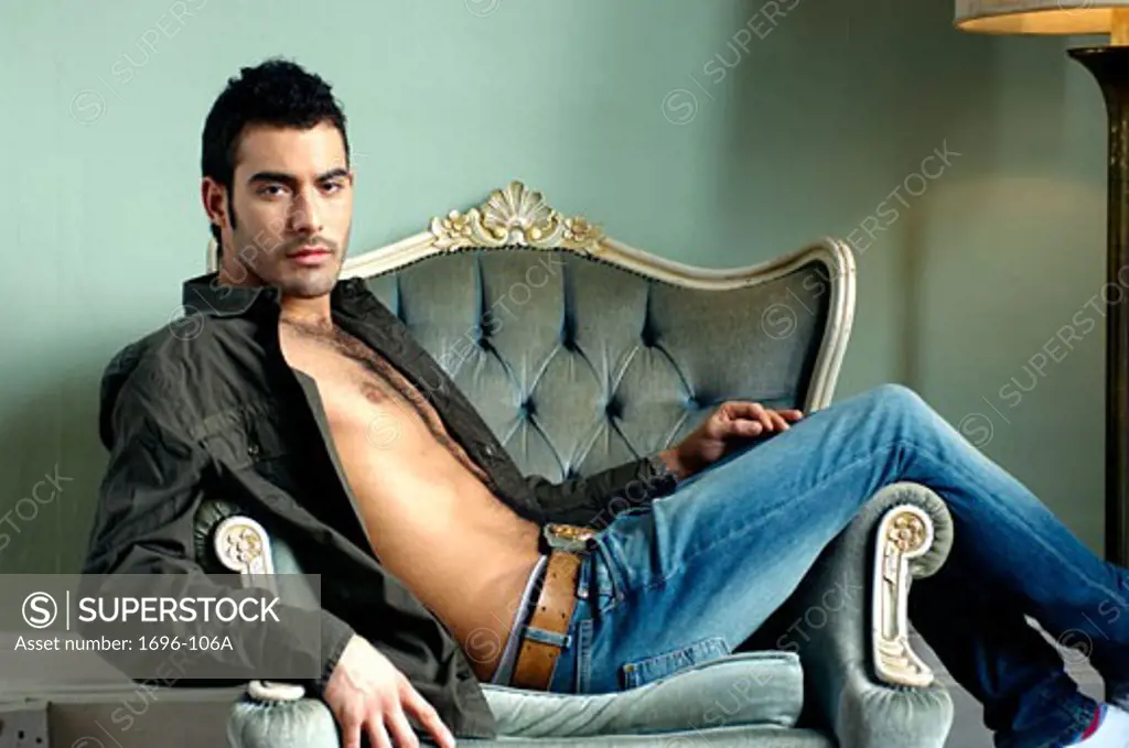Young man sitting in a chair with his shirt unbuttoned