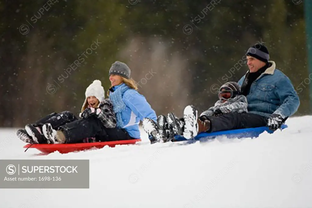 Mature couple sledding with their son and daughter