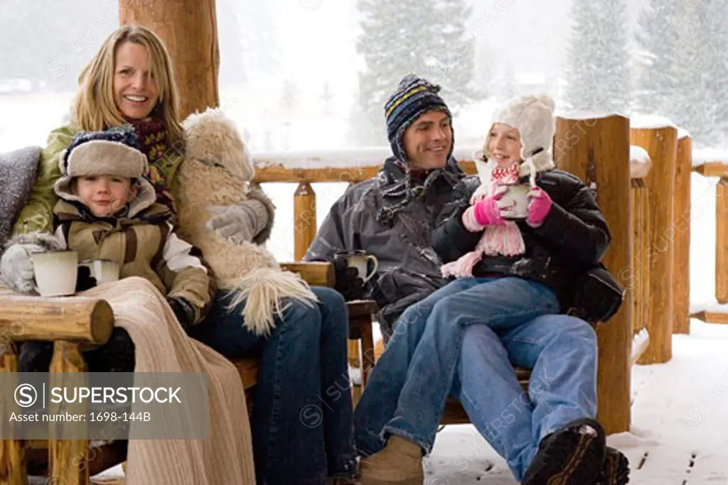 Mature couple sitting with their son and daughter on a porch