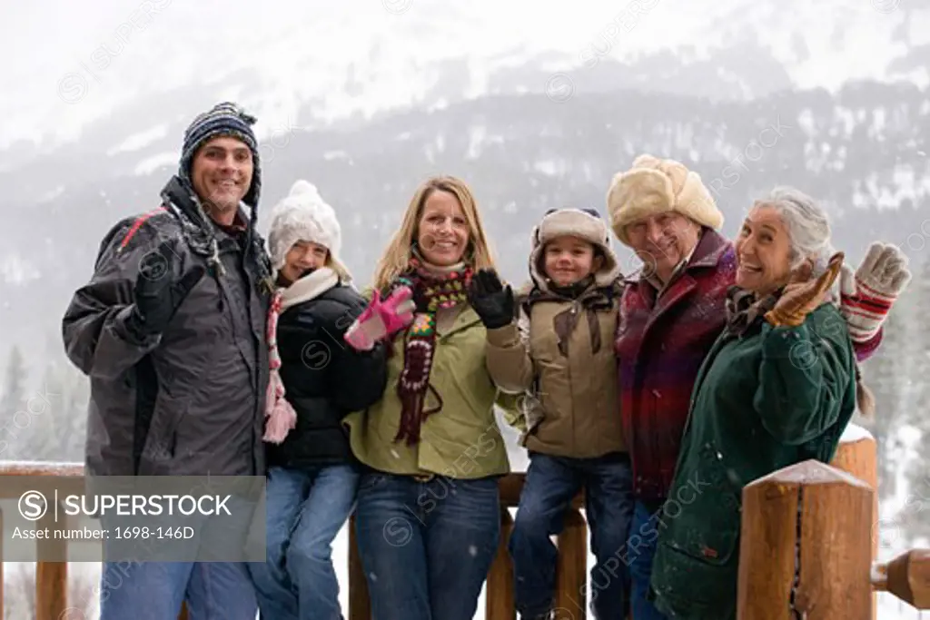 Family standing and waving with mountains in the background
