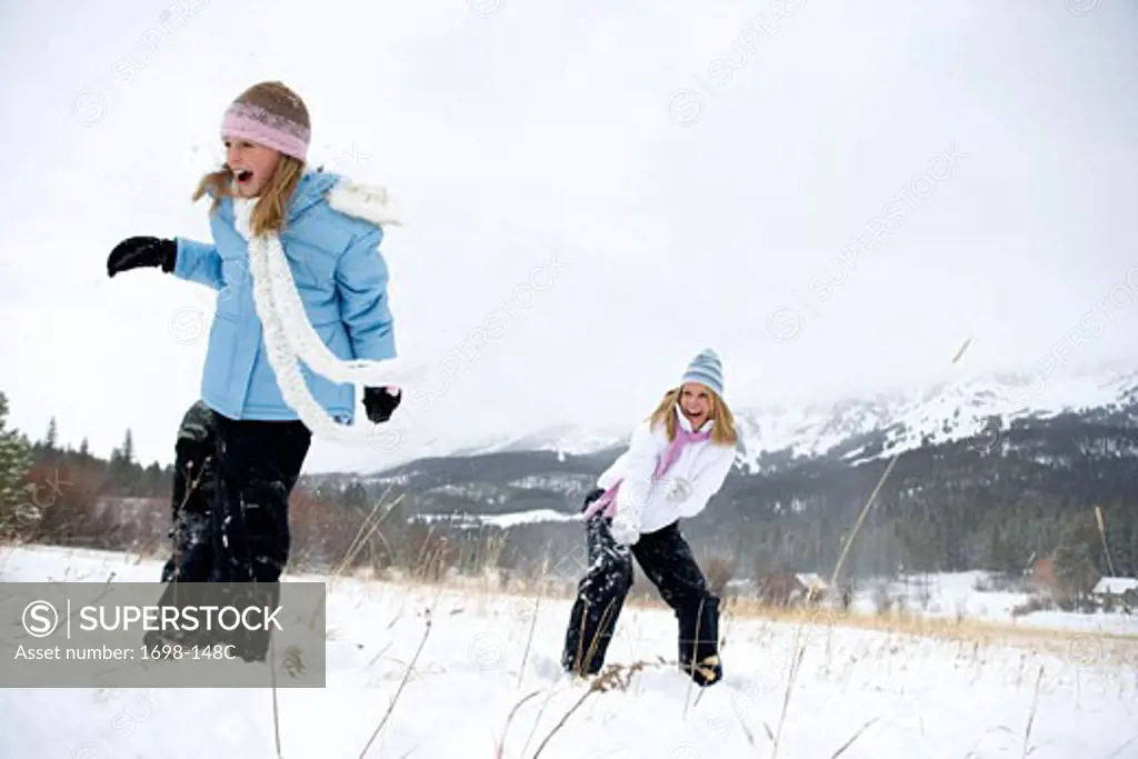 Mature woman and her daughter having a snowball fight