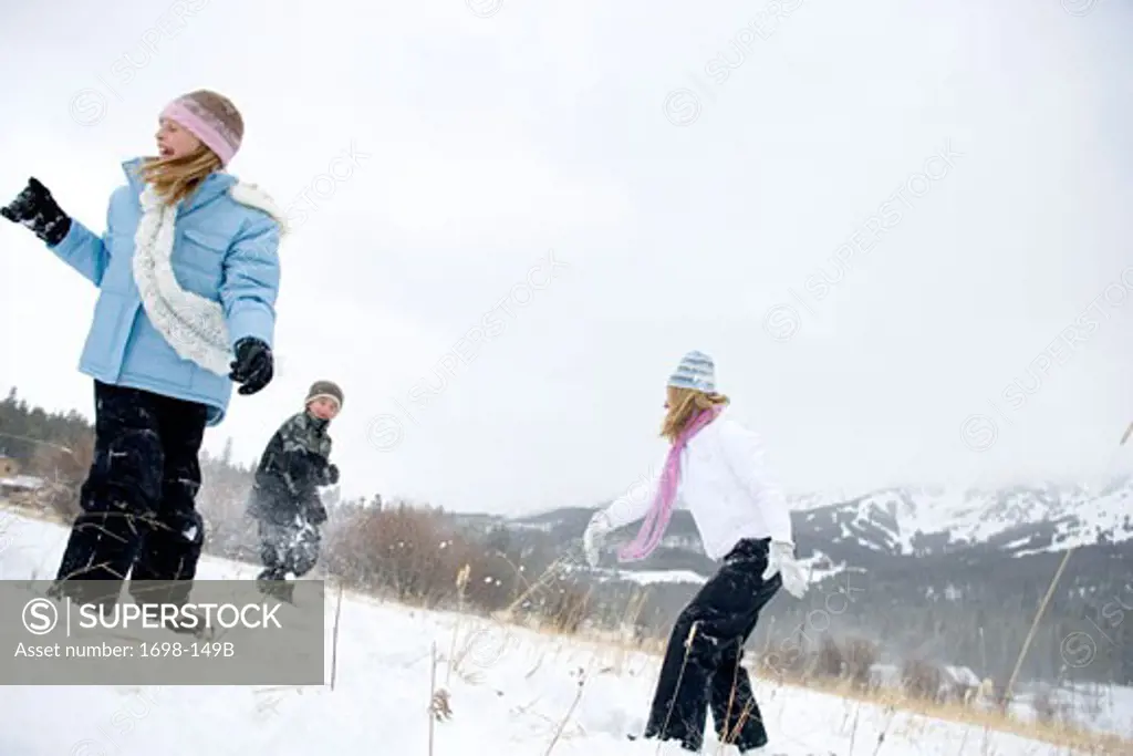 Mature woman having a snowball fight with her son and daughter