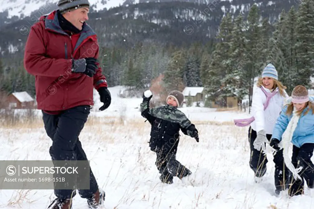 Mature woman with her son and daughter throwing snowballs at a mature man