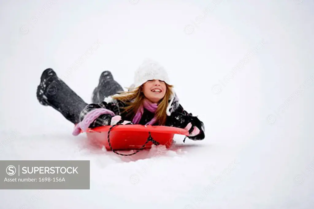 Girl lying on a sled and sledding