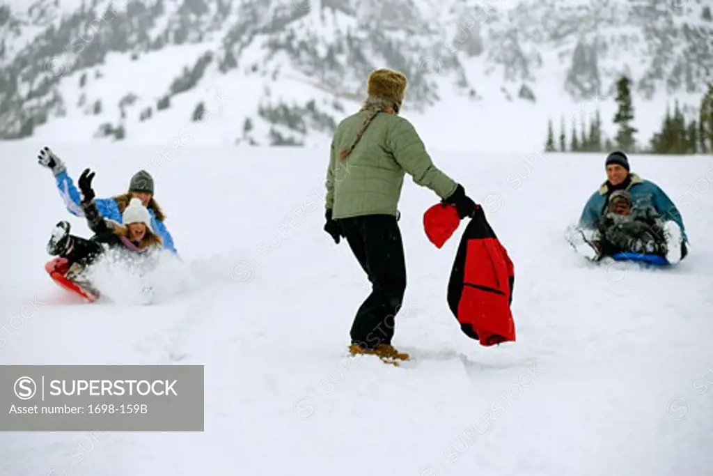 Mature couple sledding with their son and daughter