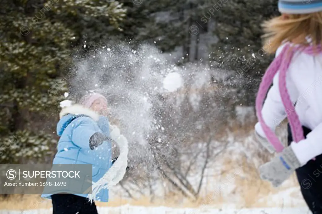Mature woman and her daughter having a snowball fight