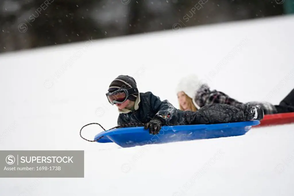 Girl and her brother sledding